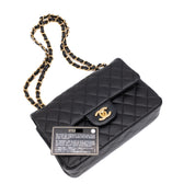 Schwarze Chanel Timeless Handtasche Double Flap Bag Small Größe aus Lammleder mit goldener Hardware Detail liegend mit ID Card