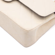 Cremefarbene Chanel Timeless Handtasche Double Flap Bag Medium Größe aus hellem Raffia Stroh Material mit goldener Hardware Ecken vorne rechts 