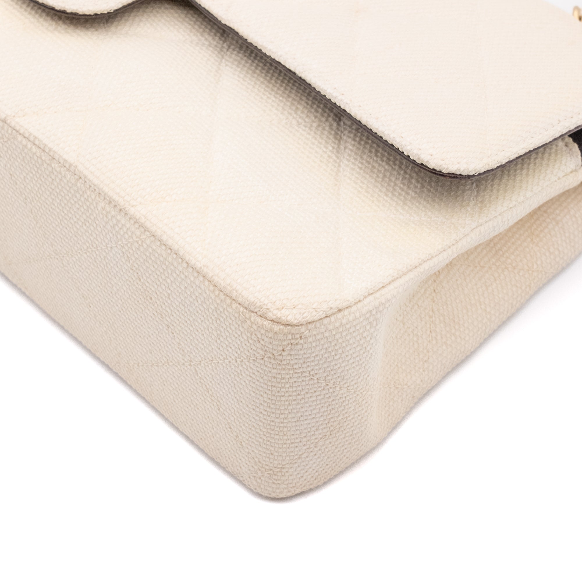 Cremefarbene Chanel Timeless Handtasche Double Flap Bag Medium Größe aus hellem Raffia Stroh Material mit goldener Hardware Ecken vorne rechts 