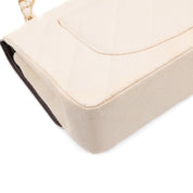 Cremefarbene Chanel Timeless Handtasche Double Flap Bag Medium Größe aus hellem Raffia Stroh Material mit goldener Hardware Ecken hinten LInks