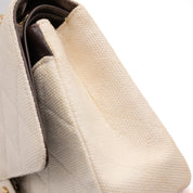 Cremefarbene Chanel Timeless Handtasche Double Flap Bag Medium Größe aus hellem Raffia Stroh Material mit goldener Hardware detail Verfärbung Seite rechts 