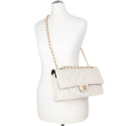 Cremefarbene Chanel Timeless Handtasche Double Flap Bag Medium Größe aus hellem Raffia Stroh Material mit goldener Hardware Tragebild