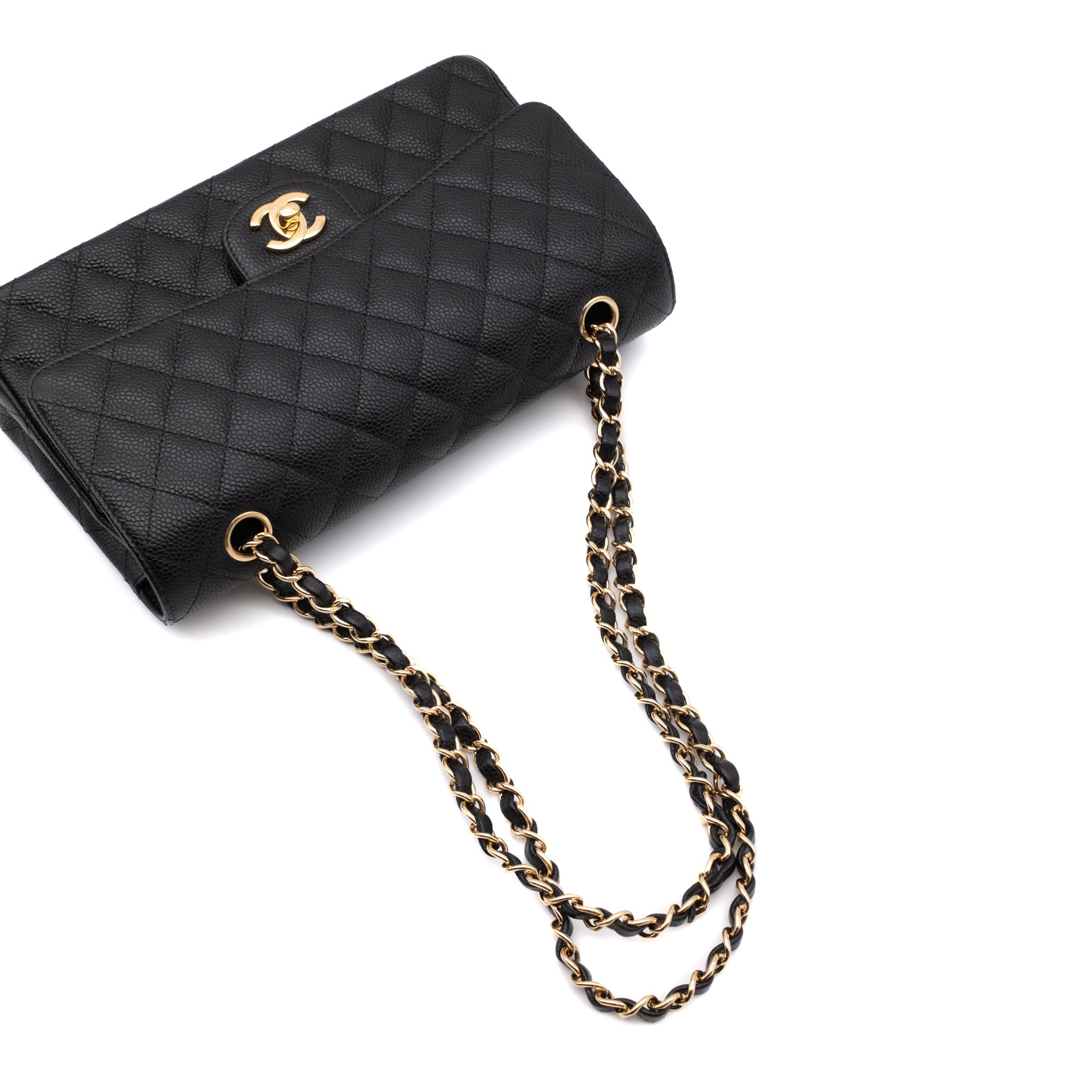 Chanel Classic Timeless Double Flap Bag in Medium Größe aus schwarzem Caviar Leder Material mit goldener Hardware liegend