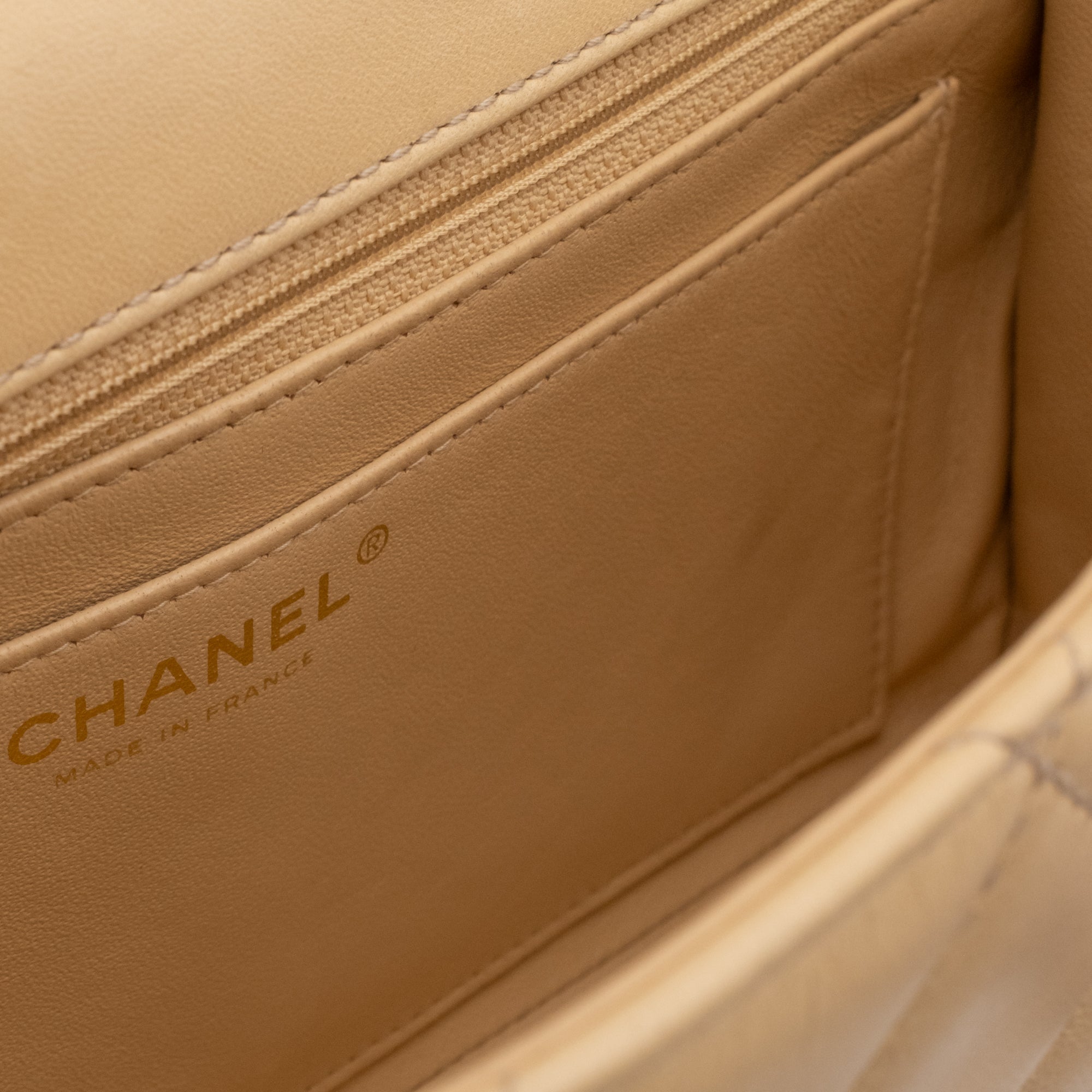 Beige Chanel Timeless Handtasche Single Flap Bag Medium Größe aus Lammleder Material mit goldener Hardware und schwarzer Trimm Zierborte Detail Innentasche