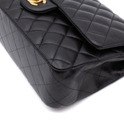 Schwarze Chanel Timeless Handtasche Double Flap Bag Medium Größe aus Lammleder mit goldener Hardware Detail Ecken Rechts vorne